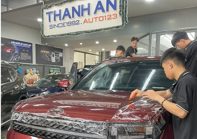 Nhân viên đang cắt và dán PPF xe ô tô với máy móc chuyên dụng.