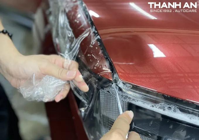 Kỹ thuật viên đang hoàn thiện các mép phim ppf trên xe Kia Cadenza.
