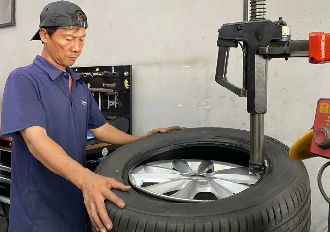 Kỹ thuật viên đang thay lốp xe Kia Sedona tại gara