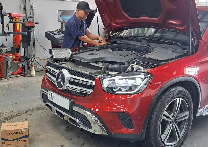 Kỹ thuật viên thay bình ắc quy Varta cho xe ô tô Mercedes tại gara