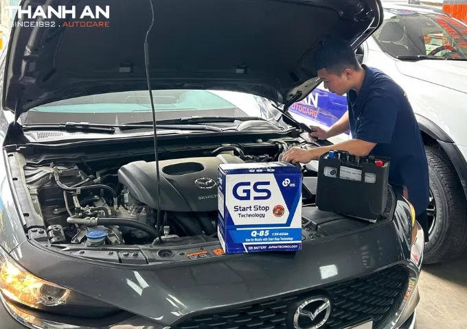 Kỹ thuật viên thay bình ắc quy GS cho xe ô tô Mazda tại gara